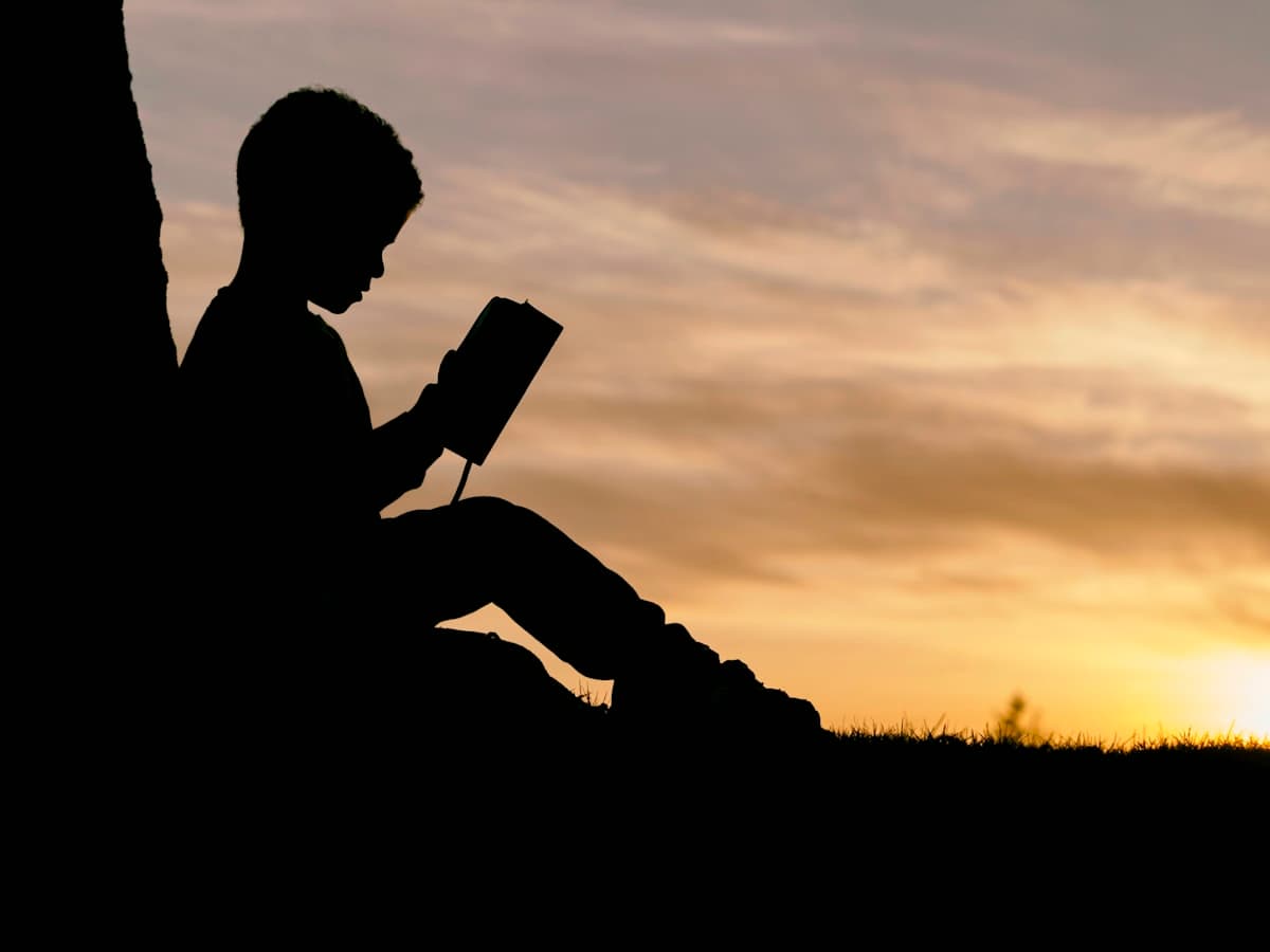طفل يقرأ كتابًا في الهواء الطلق