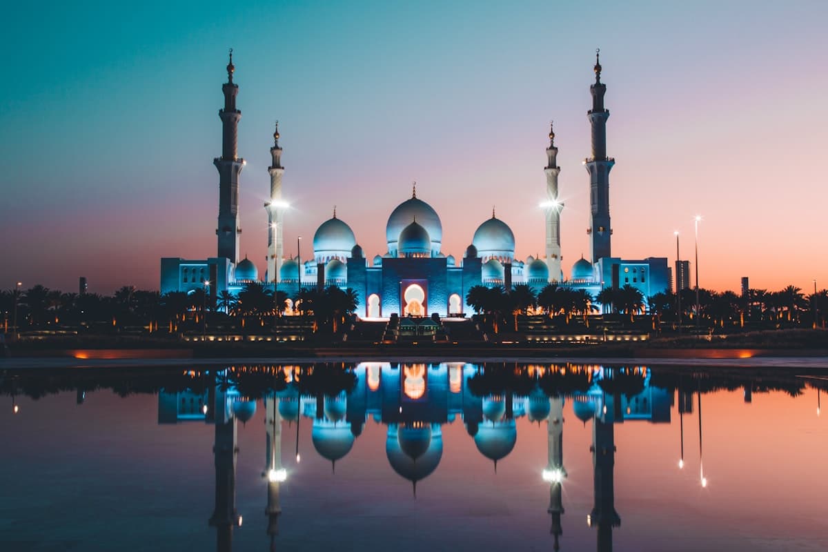 مسجد مضاء وقت الغروب وانعكاسه على الماء