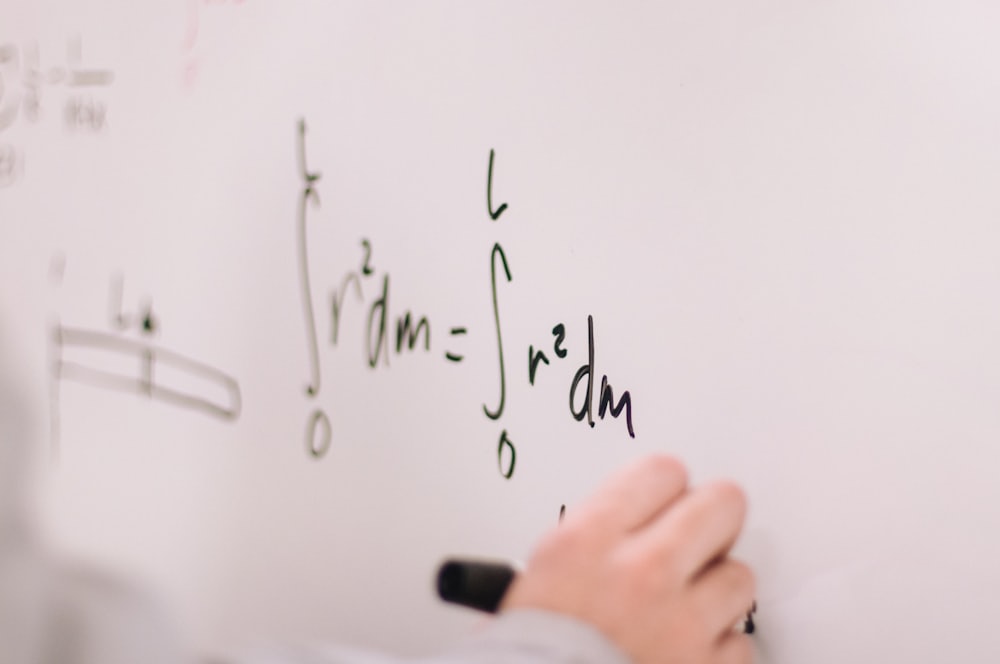يد تكتب معادلة على سبورة بيضاء