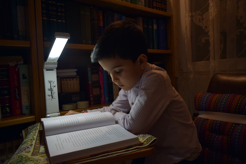 طفل يذاكر تحت ضوء مكتب في المساء